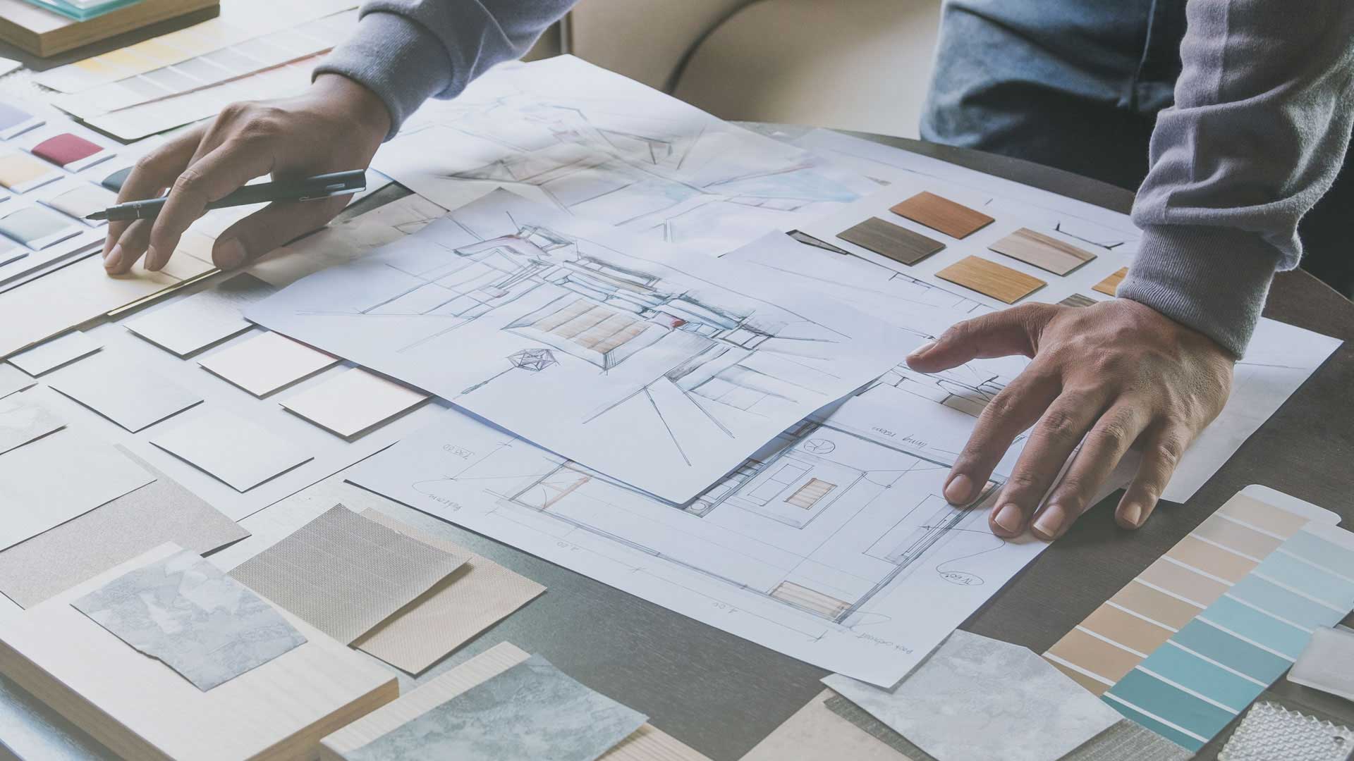 Ein Mann ist mit einem Designprojekt beschäftigt und hat verschiedene Papiere um sich herum.